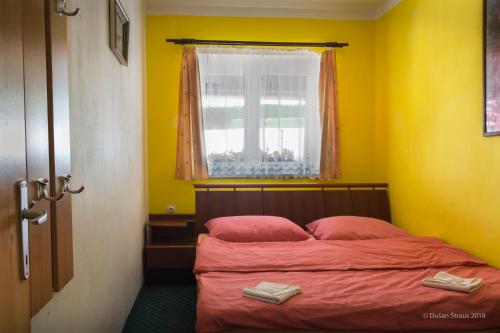 a bedroom with a bed with red sheets and a window at Penzion Pohlednička in Benecko