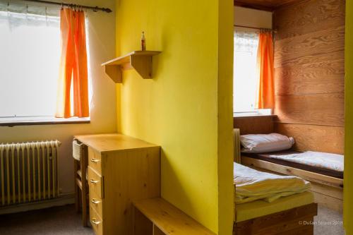 a room with two beds and a yellow wall at Penzion Pohlednička in Benecko