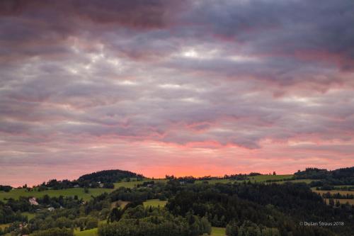 a cloudy sky over a green field with trees at Penzion Pohlednička in Benecko