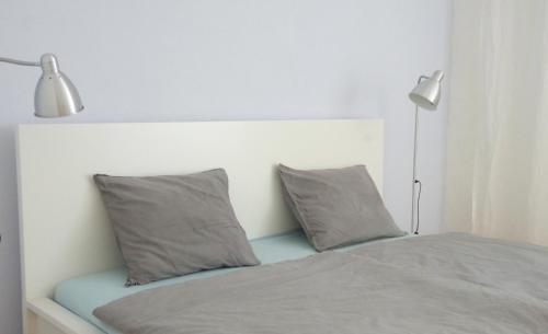 a bed with two grey pillows and a lamp at Casa Margarida Azul in Silves