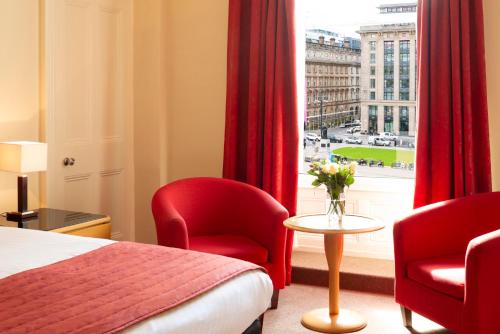 una camera d'albergo con un letto e due sedie e una finestra di Millennium Hotel Glasgow a Glasgow