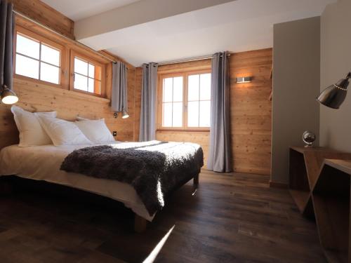 een slaapkamer met een bed met houten wanden en ramen bij Chalet l'Ardoisière in Villard-Reculas