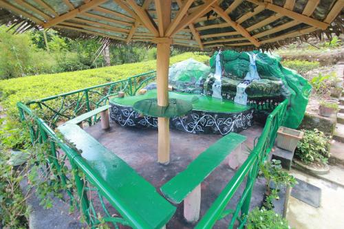 a green table under an umbrella in a garden at Narra Homestay in Maskeliya