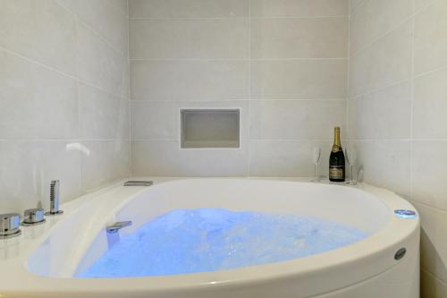 a bath tub filled with blue water in a bathroom at My Toul'House SPA in Toulouse