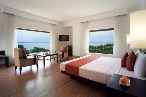 a bedroom with a bed and a desk and two windows at Vivanta Colombo, Airport Garden in Negombo