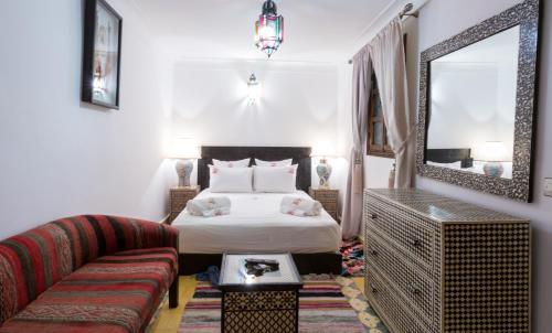 een slaapkamer met een bed, een bank en een spiegel bij Riad Ramz in Marrakesh