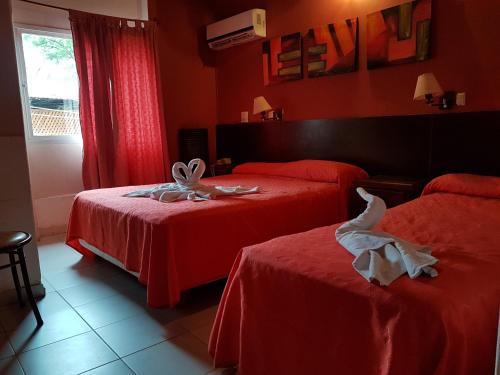 2 camas en una habitación de hotel con paredes rojas en Apart Hotel Piscu Yaco en Merlo