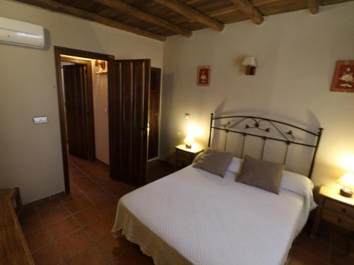 1 dormitorio con 1 cama blanca y 2 lámparas en Apartamentos Posadas De Granadilla, en Zarza de Granadilla