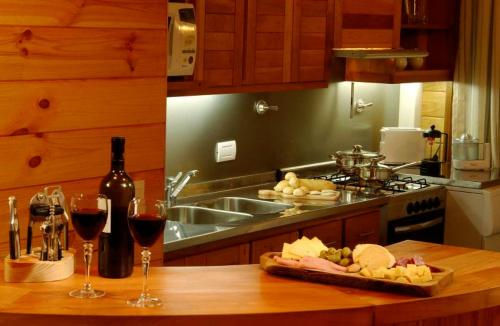 a kitchen counter with wine glasses and a plate of food at Apart del Maiten in San Martín de los Andes