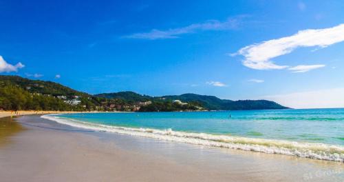 a beach with people swimming in the water at OK Phuket in Kata Beach