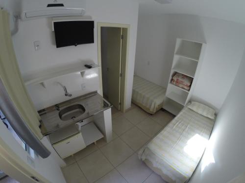 a bathroom with a sink and a tv on the wall at Pousada Morada das Nações in Balneário Camboriú