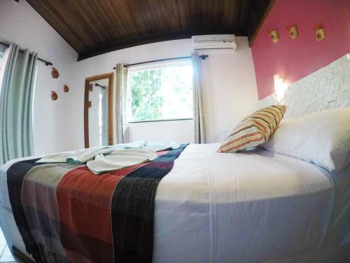 a bedroom with a bed with a colorful blanket on it at Pousada Guapuruvu in Abraão