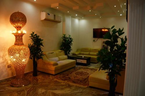 a living room with a couch and a lamp in it at Royal Suite Hotel Apartments in Al Ḩuwayl