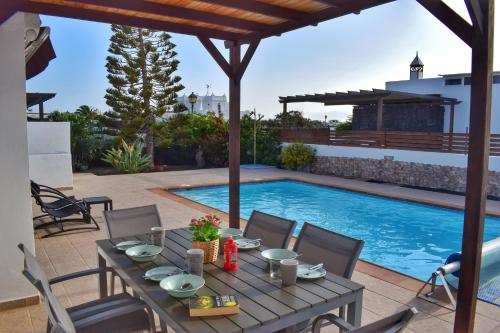 a patio with a table and a swimming pool at Villa Imogen with NEW HEATED SWIMMING POOL in Playa Blanca