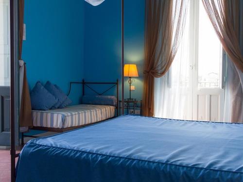 a blue bedroom with a bed and a window at Etna Hotel in Giarre