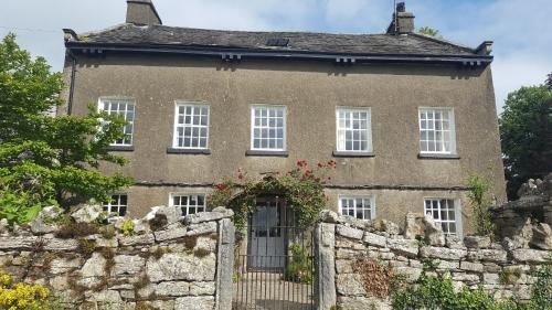 an old house with a stone wall and a fence at Witherslack Hall Farmhouse in Grange Over Sands