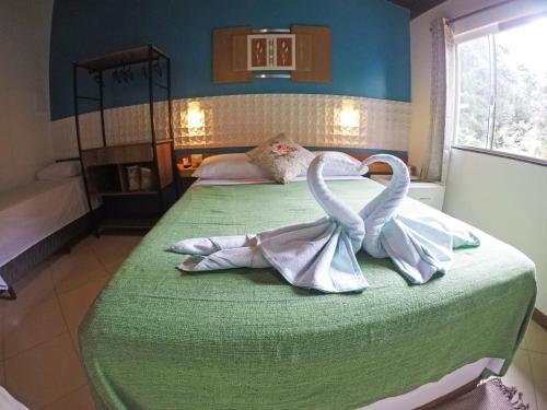 a bedroom with two swans towels on a bed at Pousada Guapuruvu in Abraão