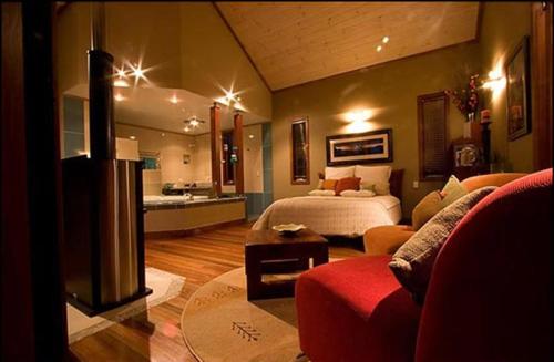 a bedroom with a bed and a living room at Cottage in The Woods, Maleny in Maleny