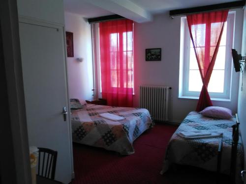 Cette chambre comprend deux lits et une fenêtre avec des rideaux rouges. dans l'établissement Le Relais De La Marche, à Aigurande