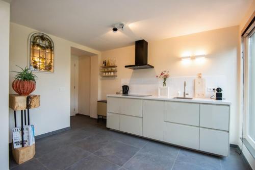 a kitchen with white cabinets and a tile floor at De Gouden Forel in Gulpen