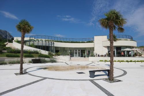 a building with palm trees and a bench in front of it at Lavender Bay Apartments D3 or D5 I by Andreas Crivellaro in Donji Morinj