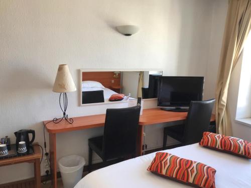 a room with a desk with a computer and a bed at Hotel Colbert in Saint-Jean-de-Luz