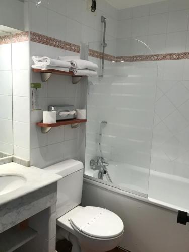 a bathroom with a toilet and a sink and a shower at Hotel Colbert in Saint-Jean-de-Luz