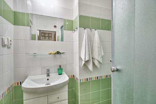 a green and white bathroom with a sink and a shower at Apartment U Medvídka in Karlovy Vary