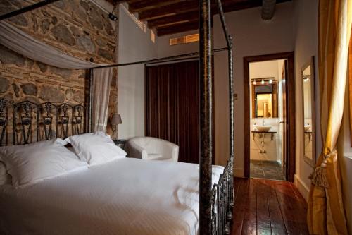 トレドにあるToledo Con Encantoの石壁のベッドルーム1室(天蓋付きベッド1台付)