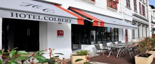 a hotel lobby with tables and chairs outside of a building at Hotel Colbert in Saint-Jean-de-Luz