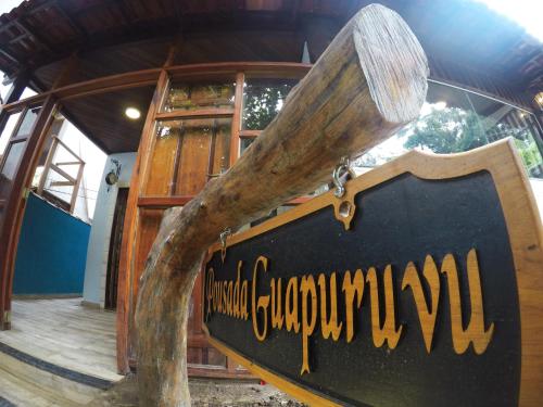 a sign in front of a building with a tree at Pousada Guapuruvu in Abraão