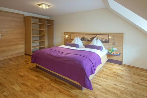 a bedroom with a large bed with purple sheets at Hotel Restaurant DAS RÖSSL in Windischgarsten