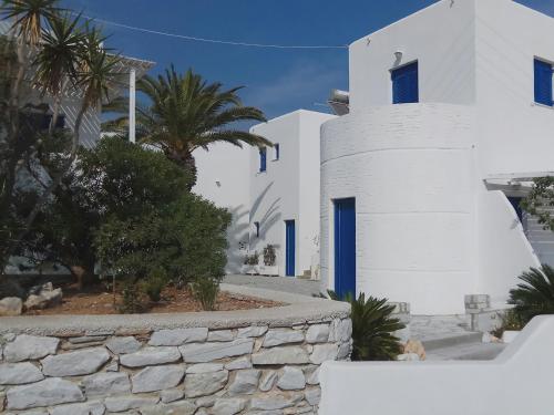 a white house with blue windows and a stone wall at Nicos Studios & Apartments in Logaras