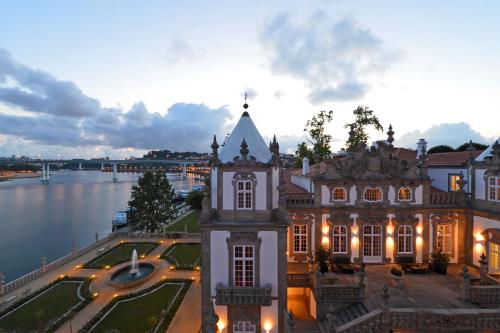 a building with a clock tower next to a river at Pestana Palacio do Freixo, Pousada & National Monument - The Leading Hotels of the World in Porto