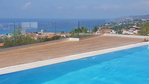a swimming pool with a wooden deck and the ocean at Appartamenti Borgo Panoramico N 5 in Tropea