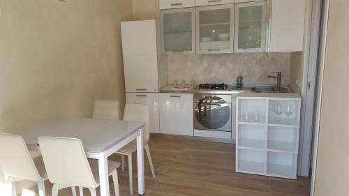 a kitchen with white cabinets and a table and chairs at Appartamenti Borgo Panoramico N 5 in Tropea