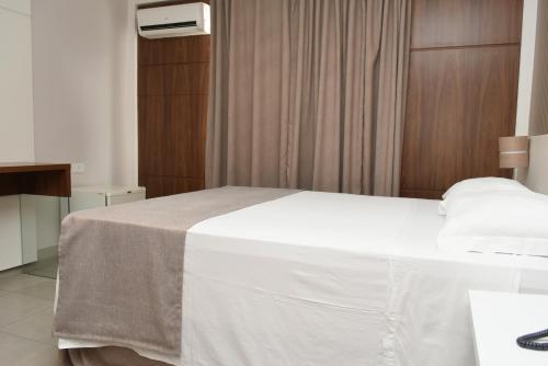 a bedroom with a large white bed in a room at Hotel Vilhar in Ivaiporã