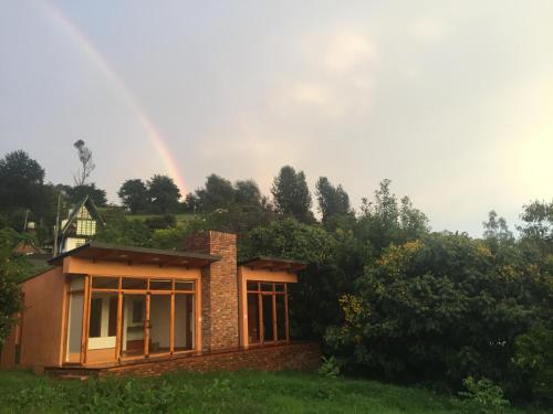 a house with a rainbow in the background at Titué Refugio , Cabañas in La Calera