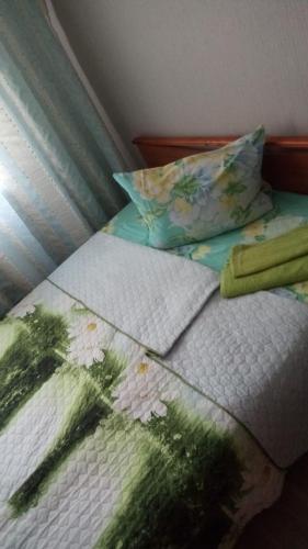 a bed with a blanket and pillows on it at 2х комн комфорт Утренний in Koltsovo