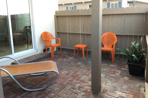 a patio with two orange chairs and a table at The Sea View Inn At The Beach in Manhattan Beach
