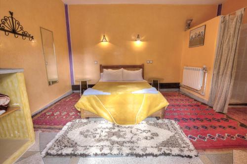 a bedroom with a bed with a yellow comforter at Hotel Baddou in Tamtetoucht
