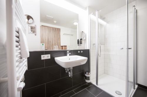 a white bathroom with a sink and a shower at Hotel Saxenhof in Dermbach