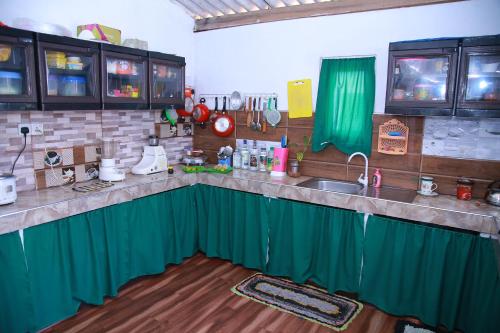 una cocina con cortinas verdes y fregadero en Weerakoon Garden Guest, en Hikkaduwa