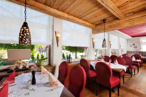 ein Esszimmer mit roten Stühlen, Tischen und Fenstern in der Unterkunft Gasthaus Sonne in Altusried