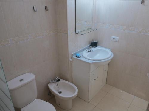 a white bathroom with a toilet and a sink at Brisas del Mar in Los Abrigos