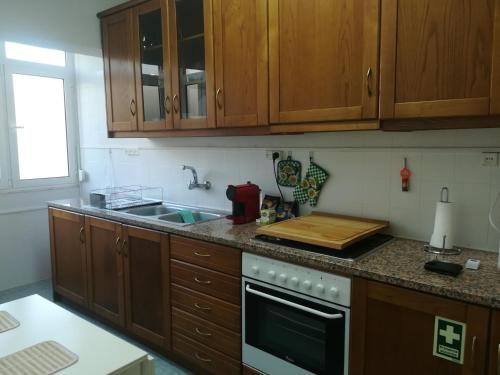 a kitchen with wooden cabinets and a stove top oven at Casa do Pedro - Lisbon South Bay in Almada