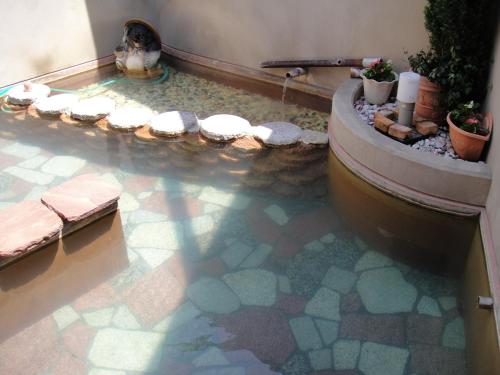 a bathroom with a bath tub with a tile floor at Daymaruya Ryokan in Yamanouchi