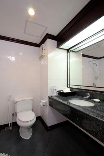 a bathroom with a toilet and a sink and a mirror at The Front Village - SHA Plus in Karon Beach