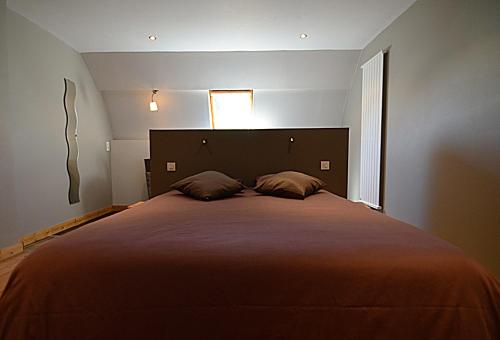 een slaapkamer met een groot bed met 2 kussens bij La Citadine-Gîte citadin in Neufchâteau