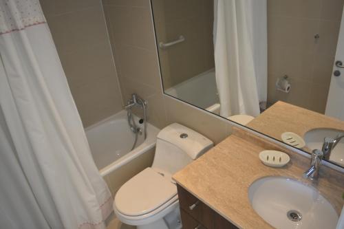 y baño con aseo, lavabo y espejo. en Costa Puyai - Exclusivo Departamento en primera línea- Playa Punta Puyai, en Papudo